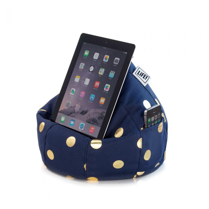A dark blue iCrib tablet holder iPad rest with metallic gold dot coin print. A mobile phone sits in the storage pocket