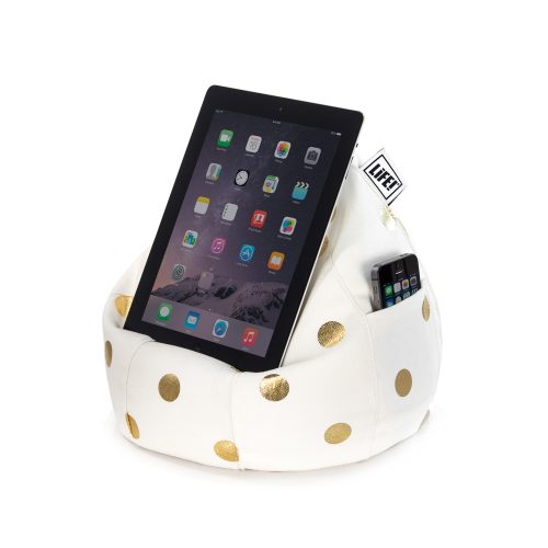 A iPad, tablet or portable device sits on the white iCrib tablet holder, iPad rest, book stand, with metallic gold coin dot print. A mobile phone sits in the pocket.