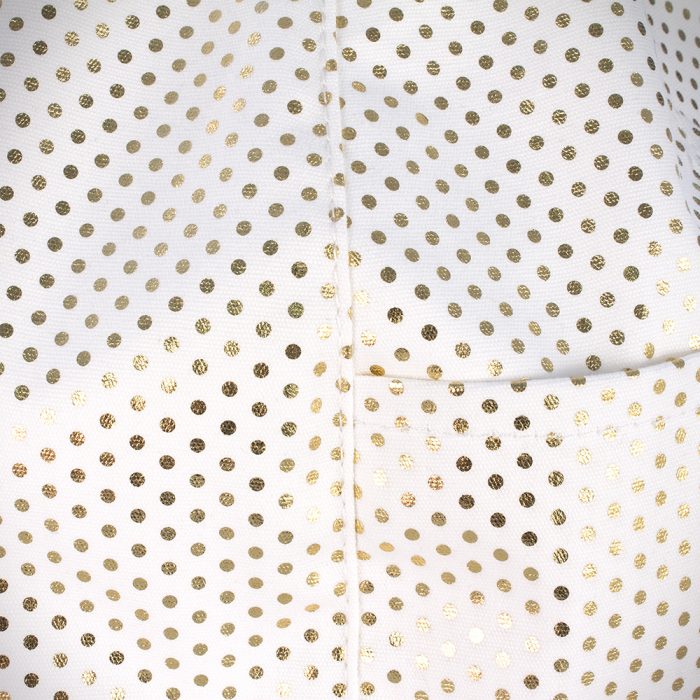 A close up of the white fabric with small metallic gold dots used in the white gold dust iCrib