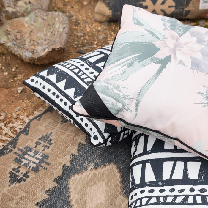 Close up of the kateen and bermuda print indoor outdoor cushions on rocky ground