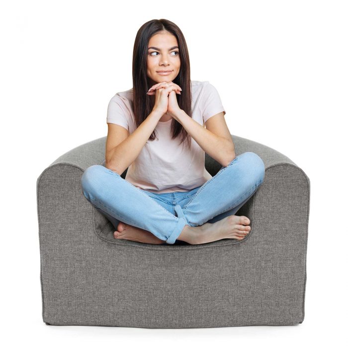 Women sits cross legged on a foam armchair with grey linen look material