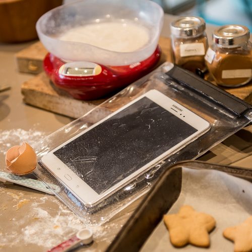Dryz tablet protector shown with tablet inside and cooking mess around, flour, eggshells, cookies and scales