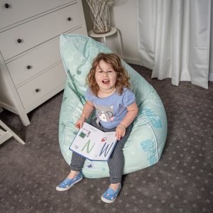 A toddler sits on a sea of love print bean bag featuring mermaids, sailors and dolphins